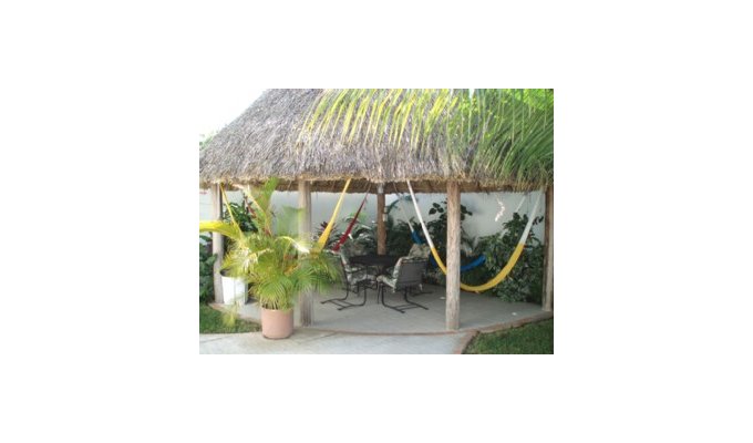 A large palapa covered patio with double sized hammocks
